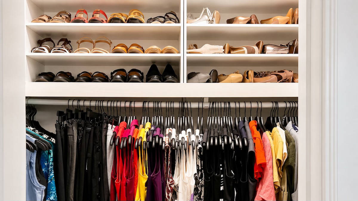 Organized closet with shoe shelving and color-sorted hanging clothes by Nola Organizers
