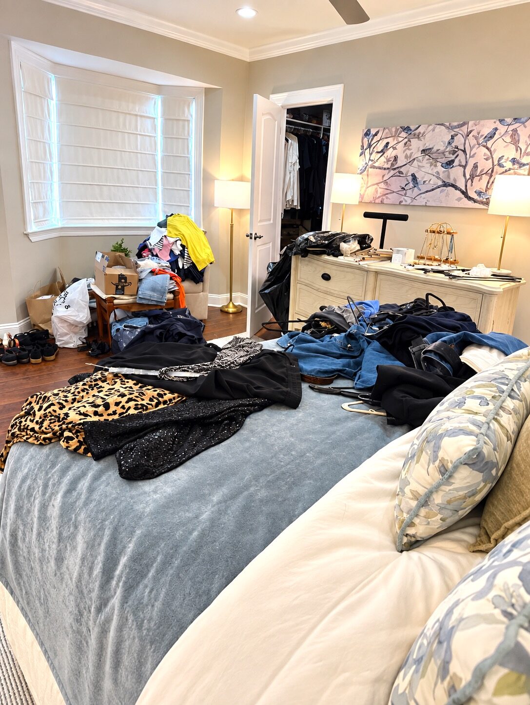 Bedroom before organizing, with clothes on the bed and belongings on a chair and dresser