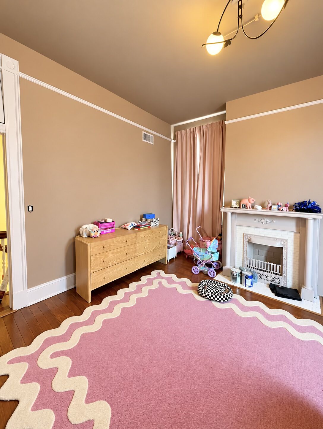 Dresser and grouped toys in the unpacked pink bedroom, with clear floor space