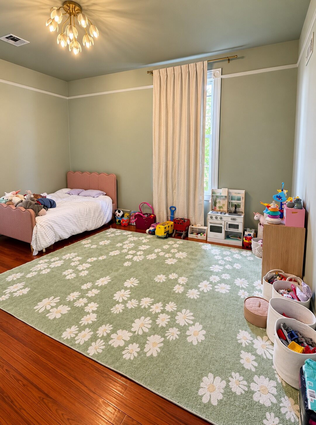 Sage-colored children’s bedroom after organizing, with toys in baskets and open space on the rug