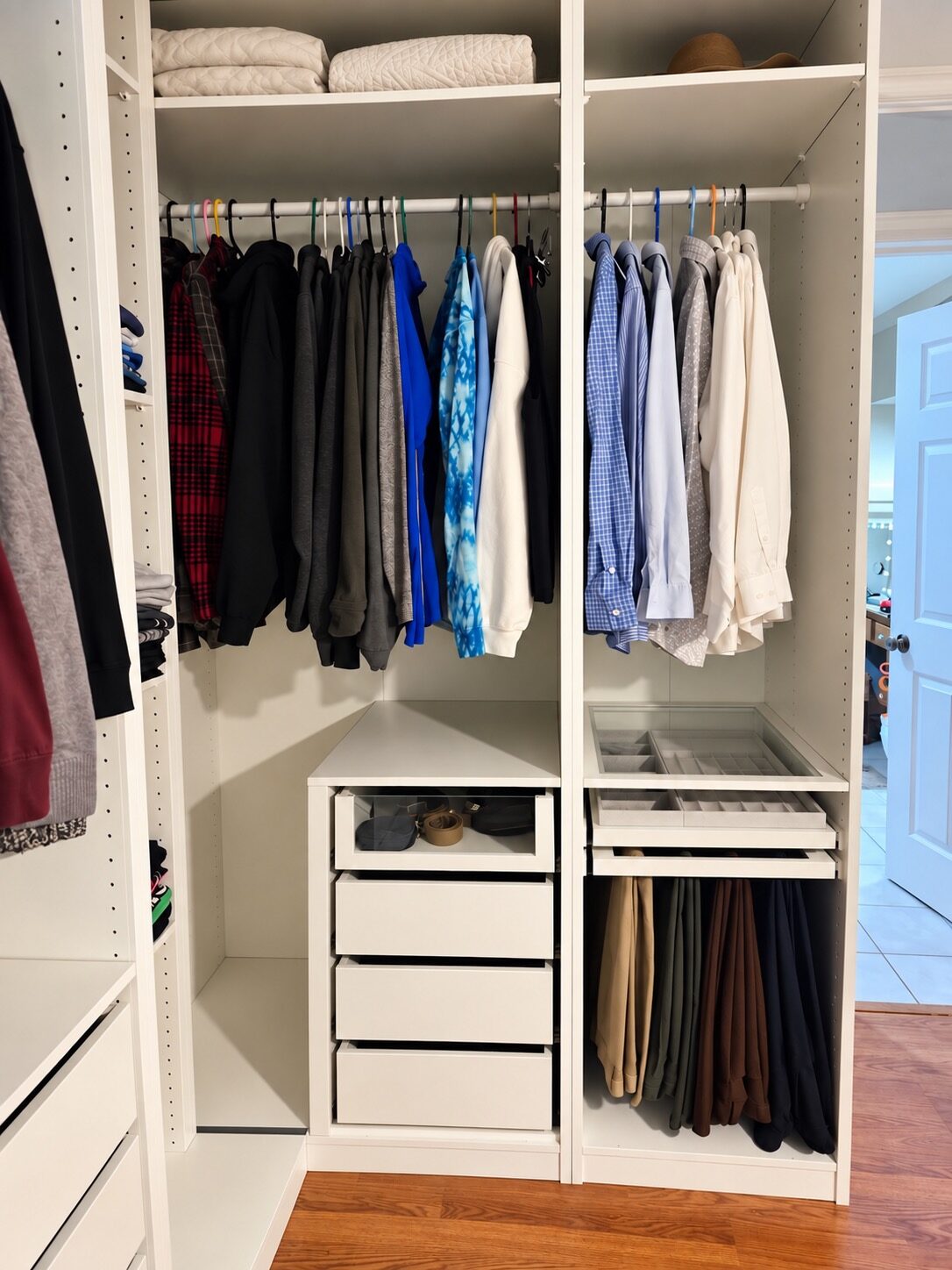 Organized hanging clothes, upper-shelf linens, accessories, and pants in the new closet
