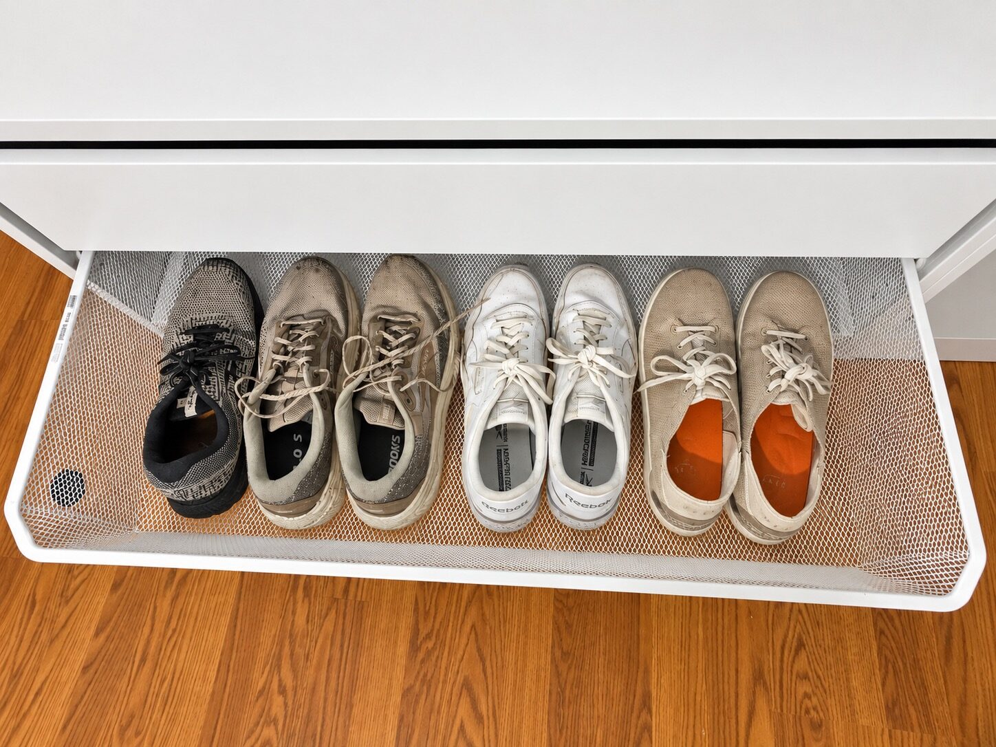 Shoes arranged in a pull-out mesh tray in the custom closet