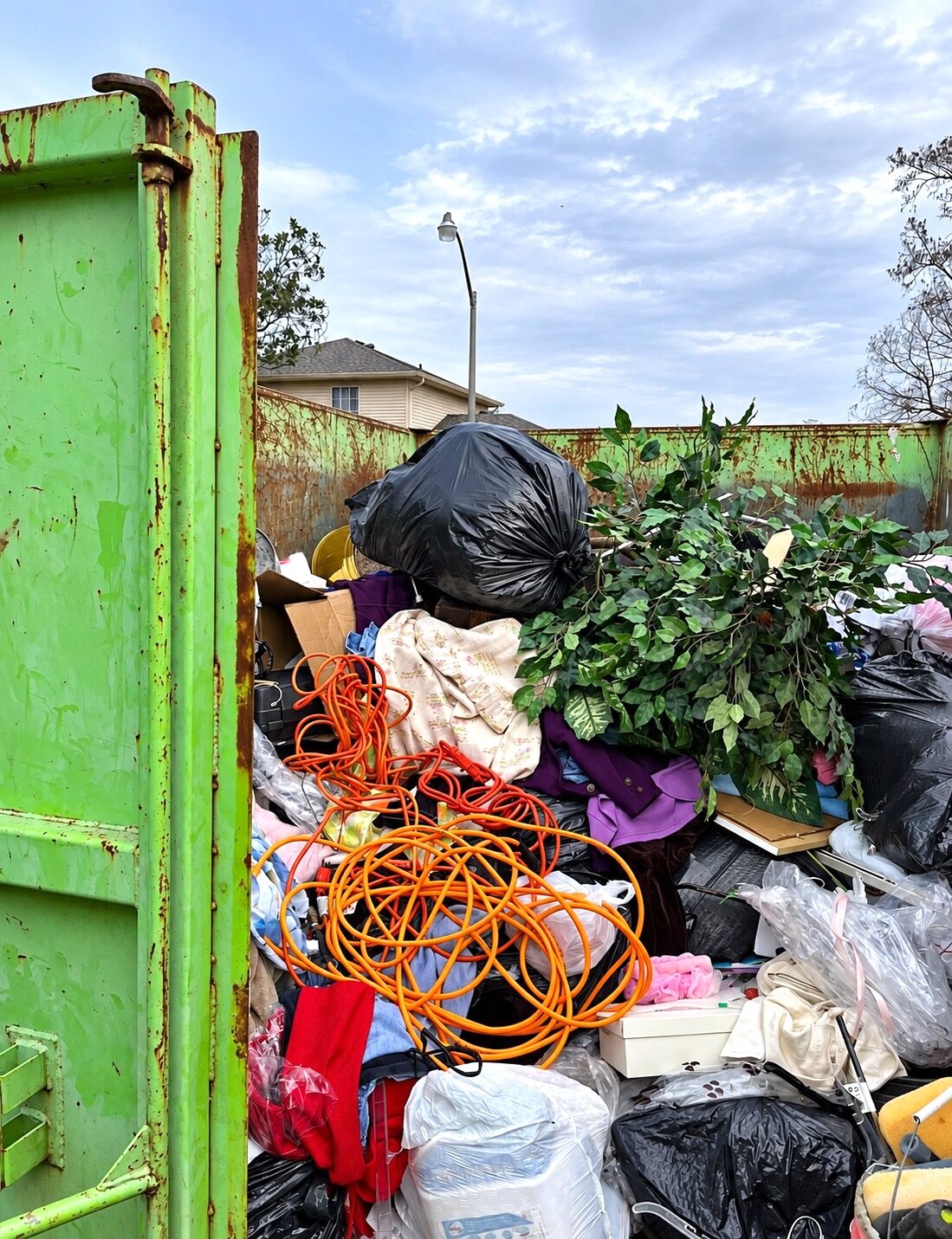 Client-rented dumpster filled with discarded items during a New Orleans garage decluttering project