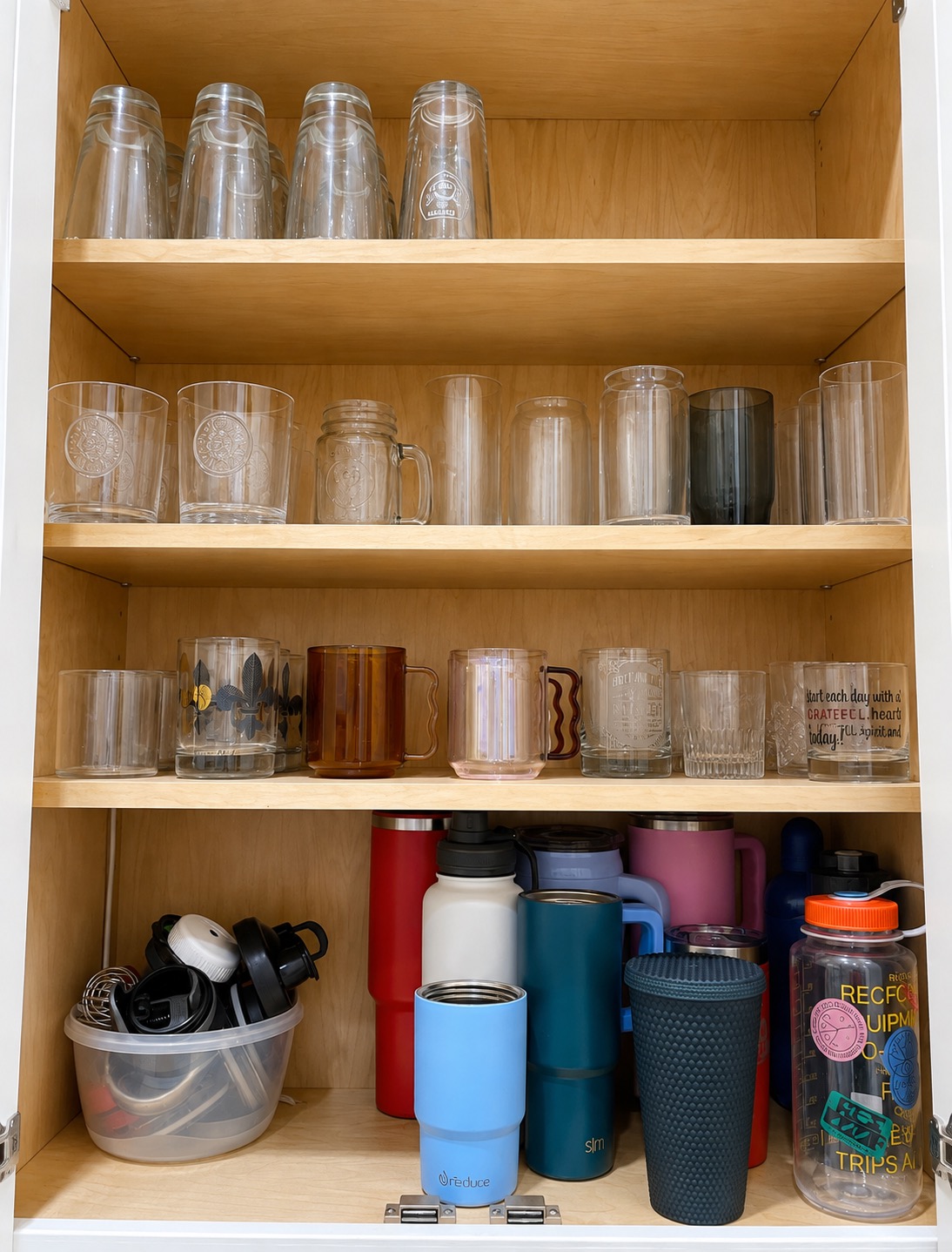 Glasses and cups arranged in an organized kitchen cabinet