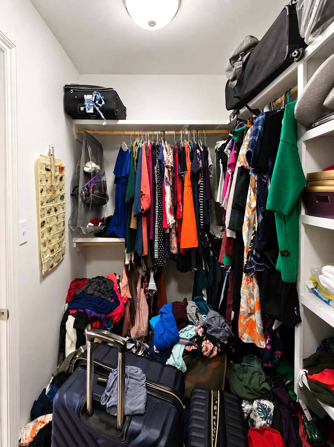 Clothing, luggage, and accessories in a New Orleans walk-in closet before sorting