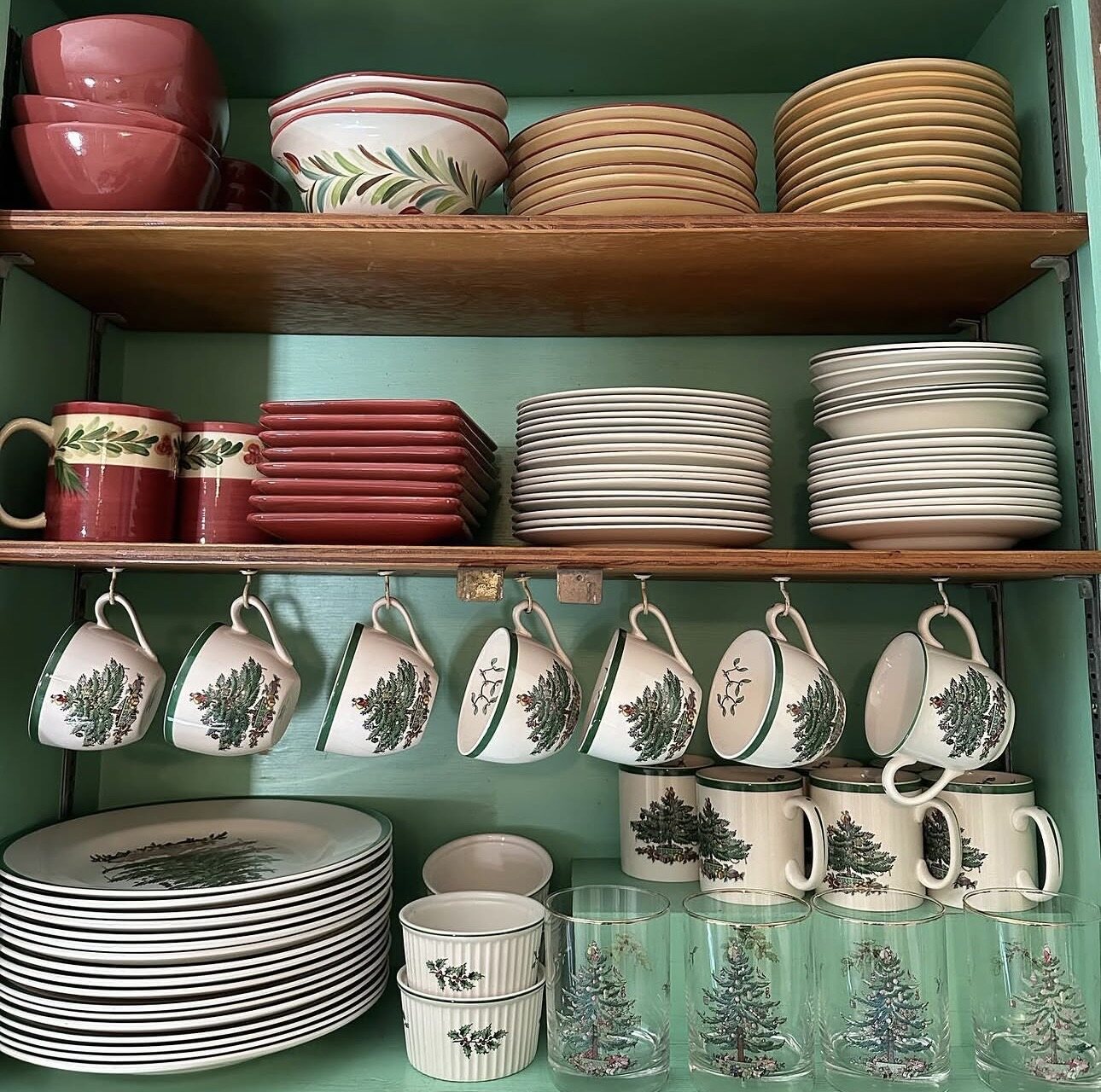 Christmas dishes, mugs, glasses, and serving pieces organized in a cabinet
