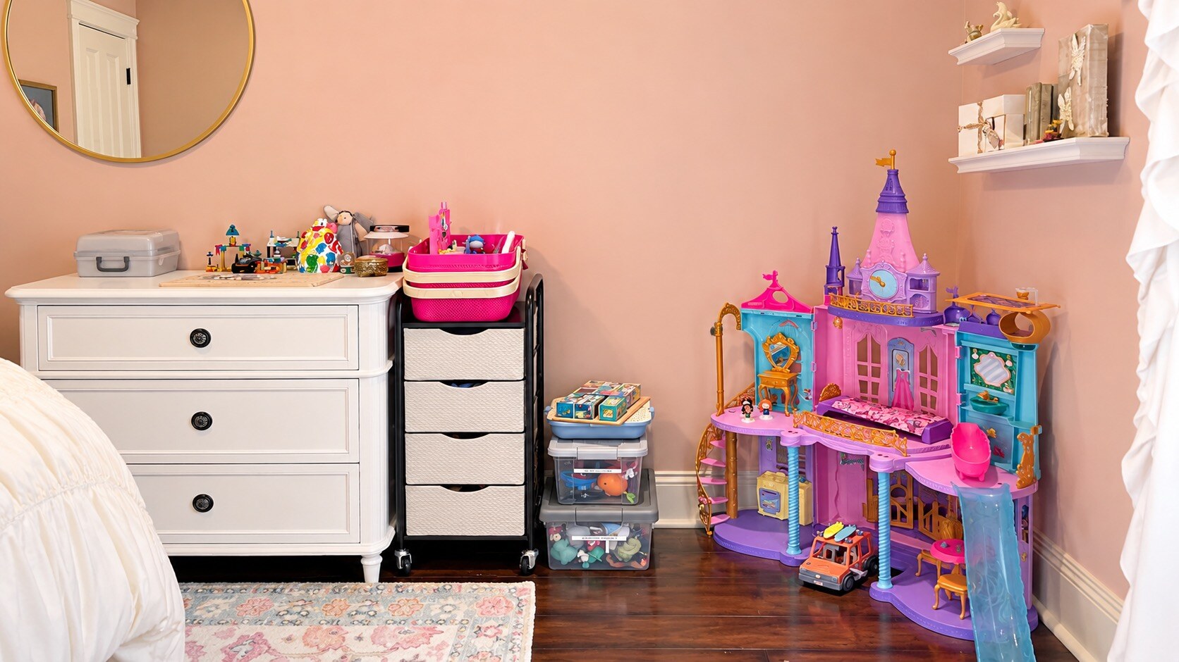 Child’s bedroom play corner with a white dresser, toy storage drawers, clear bins, and a princess dollhouse
