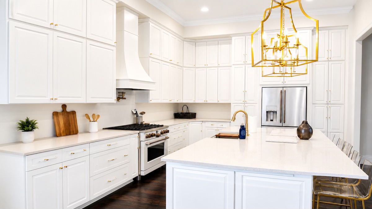 Clean organized kitchen with white cabinets and wood island by Nola Organizers