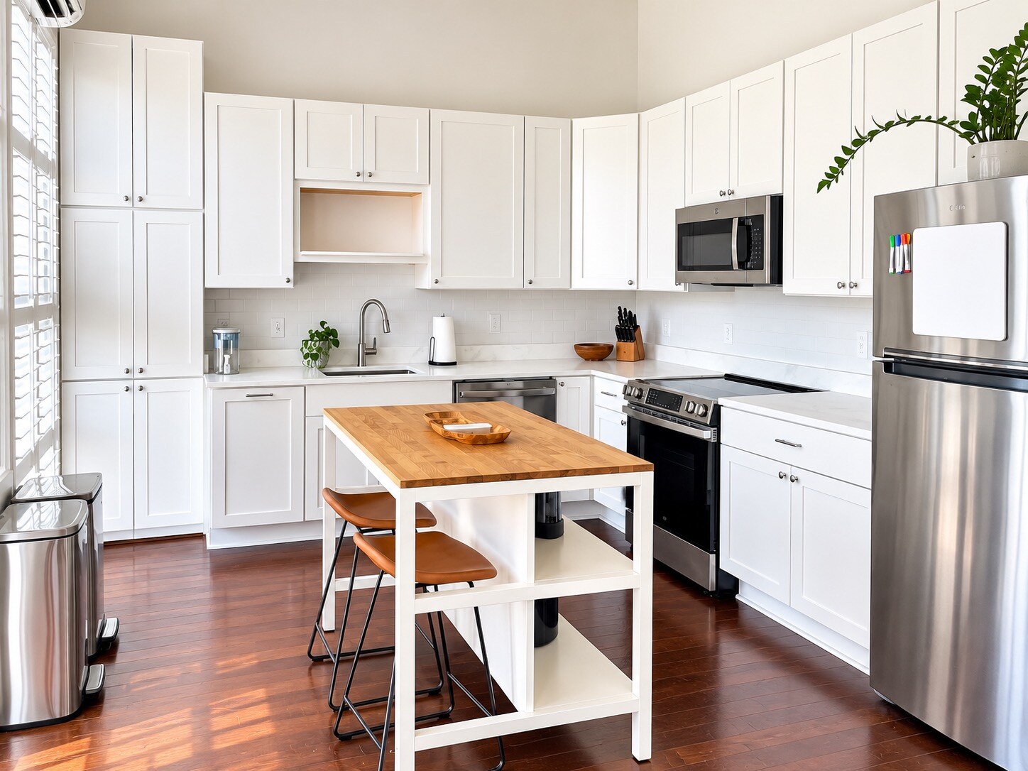 Bright organized kitchen with white cabinets, clear countertops, and a wood-topped island