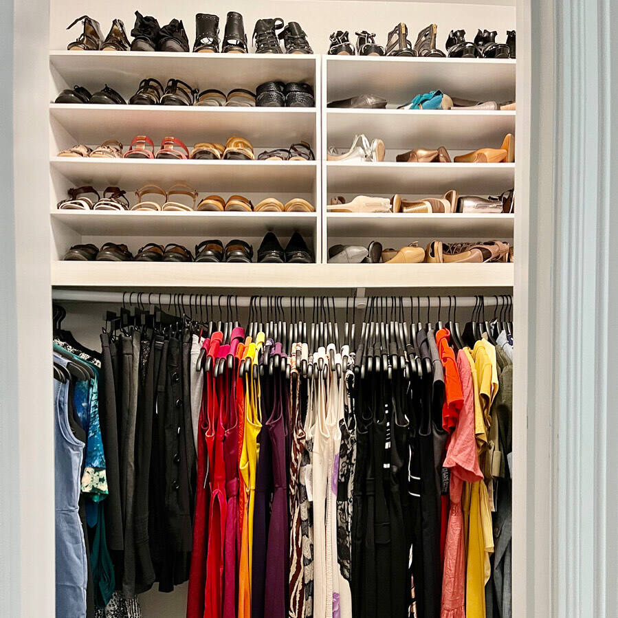 Organized walk-in closet with clothing sorted by category and color by Nola Organizers
