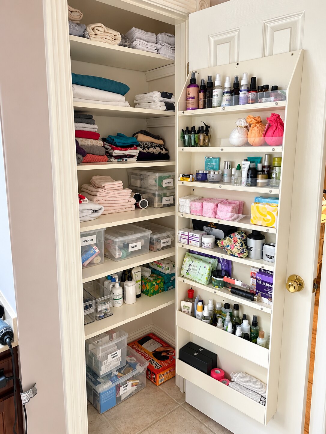 Bathroom and linen closet arranged with clear labeled bins and accessible supplies